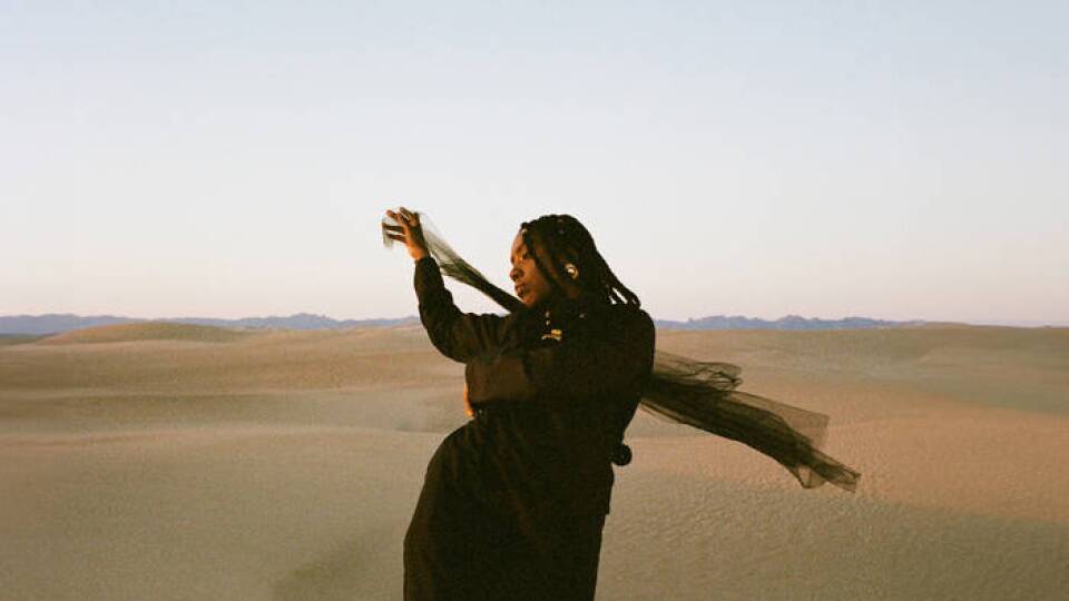 A person wearing all black standing in a desert