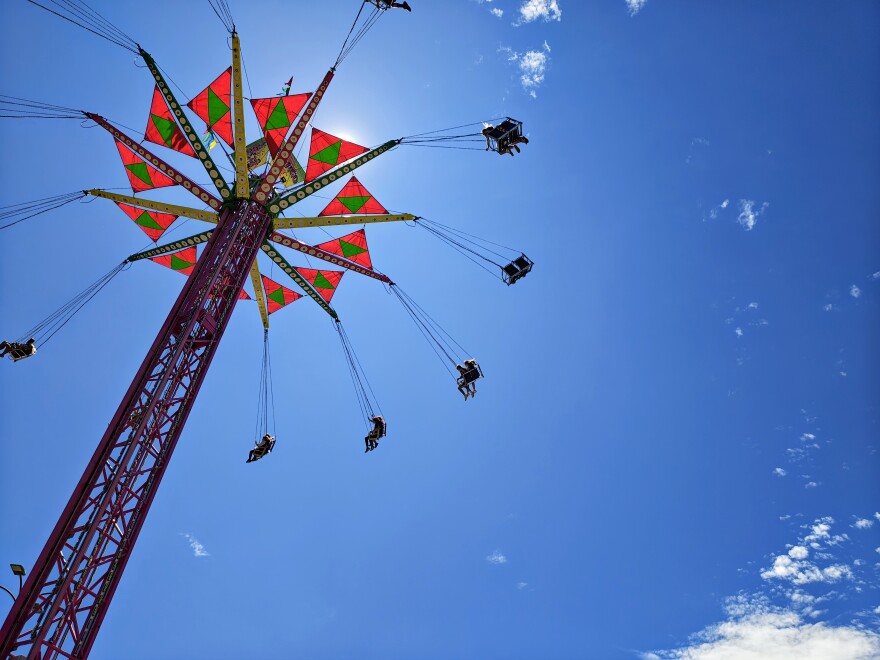 A photo looking up toward a carnival ride which features swings suspended from a tower. 