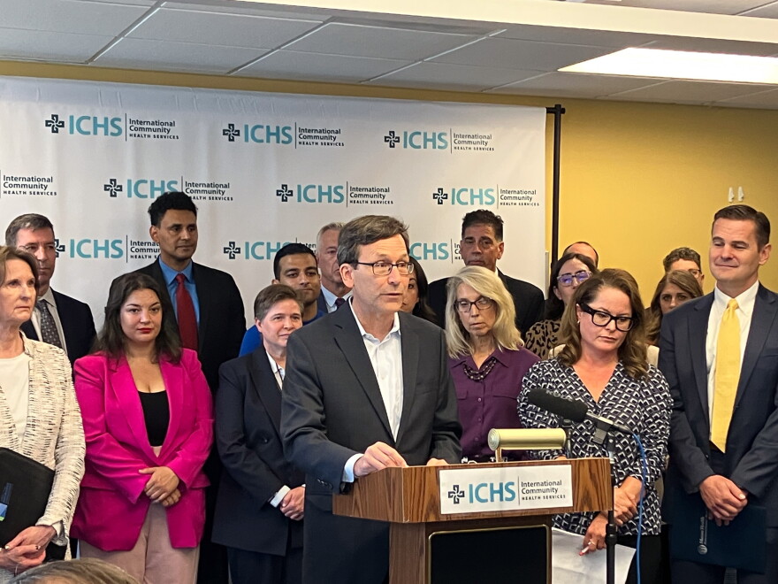 Gov. Bob Ferguson stands at a podium with a crowd behind him. 