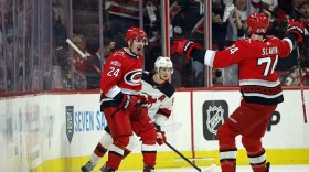 Carolina Hurricanes' Seth Jarvis (24) celebrates his goal with Jaccob Slavin (74) with New Jersey Devils' Jack Hughes (86) during the first period of Game 1 of an NHL hockey Stanley Cup second-round playoff series in Raleigh, N.C., Wednesday, May 3, 2023.