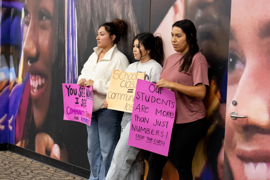 Tulsa community members hold protest signs at the back of the Tulsa Public Schools Board of Education meeting Monday night.