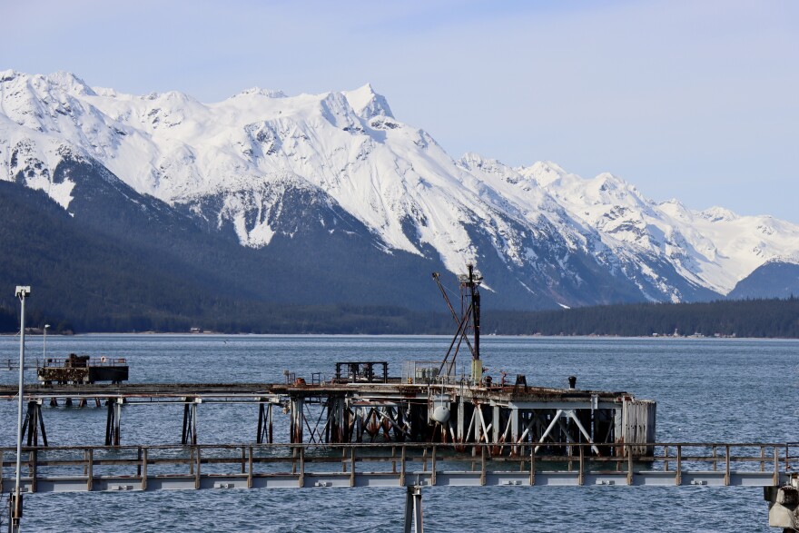 A dock in an inlet with steep, snowy mountains in the background.