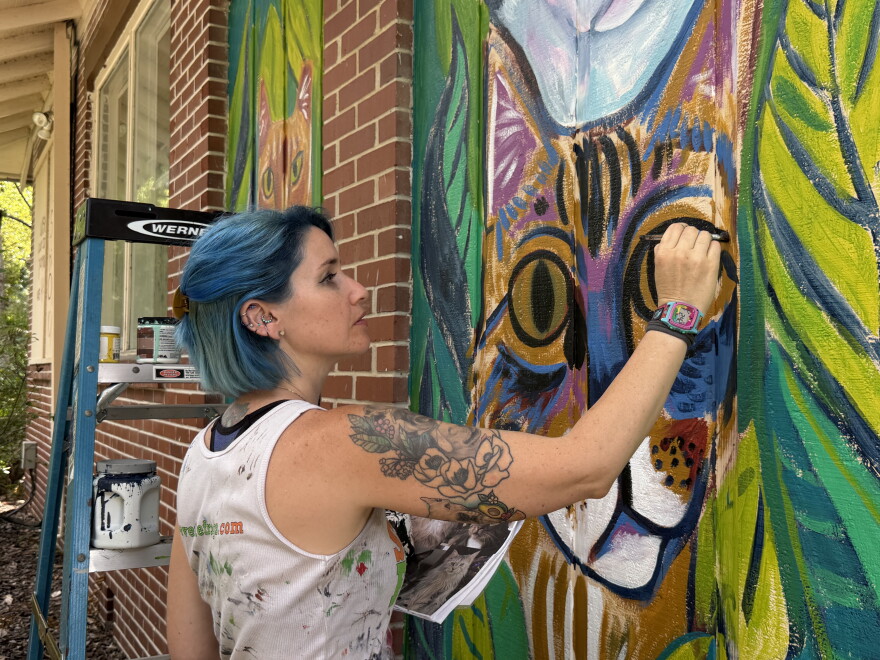 Samm Wheman adds touches to capture each cat's personality. (Genesis Trujillo/WUFT News)