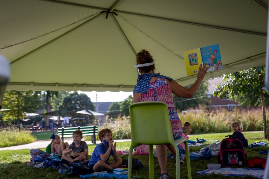 Judy Taylor, a first-grade teacher at the Forsyth School, uses a face shield while reading to students in an outdoor classroom. The private school is keeping students in first grade and up outside.