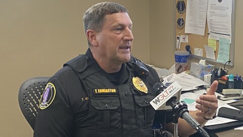 Police officer sits at his desk speaking into a microphone