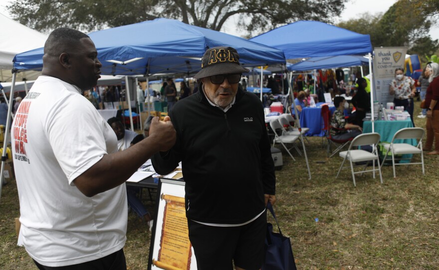 Maress Scott and Kerfoot Lewis shake hands during the 2022 Publix Tampa Bay Collard Festival in St. Petersburg, Florida, on Saturday, February 19, 2022. Photo by Octavio Jones for WUSF