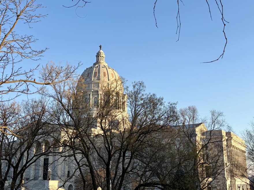 The dome of the Missouri state capitol building is visible through tree branches. 