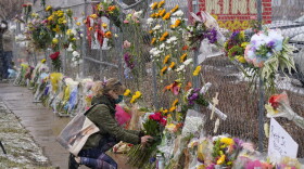 A mourner leaves a bouquet of flowers along a fence put up around the parking lot where a mass shooting took place in a King Soopers grocery store on Tuesday, March 23, 2021, in Boulder, Colo. (David Zalubowski/AP)