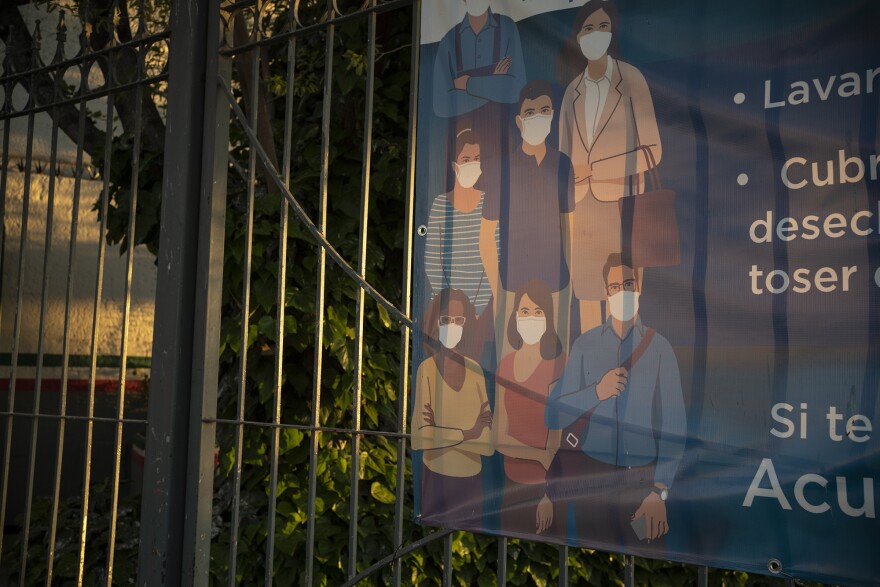 A poster near the Paso del Norte International Bridge encourages citizens to wear masks and wash hands to protect against infection from COVID-19. Both Ciudad Juárez and its sister city El Paso, Texas, have put in place stay-at-home orders, but migrants p