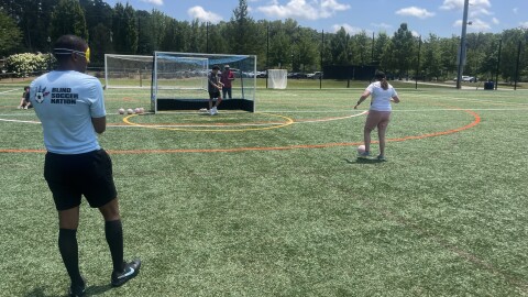 A dozen visually impaired people practice shooting on a soccer field in Matthews.