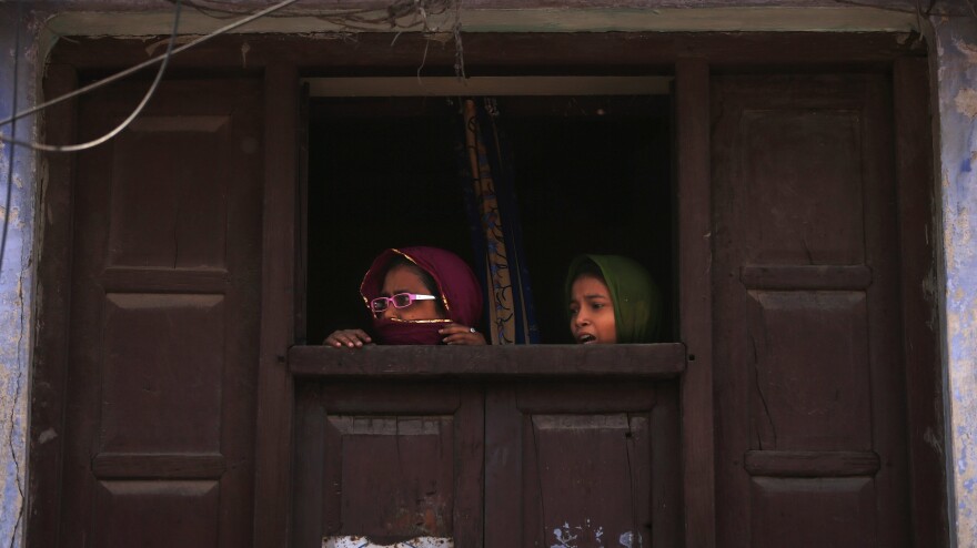 Muslim women watch Modi's rally move by in Varanasi. Most Muslims oppose Modi and fear that he would cut them out of the region's growing prosperity.