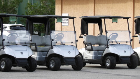 Three parked white golf carts.