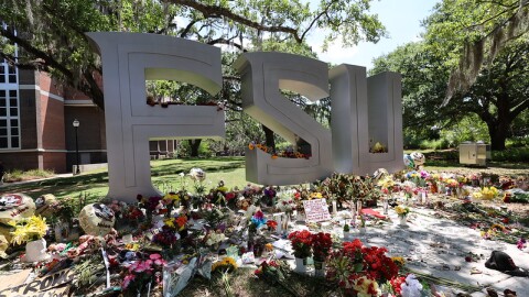 large silver letters spell FSU, many bouquets of flowers are left at the base