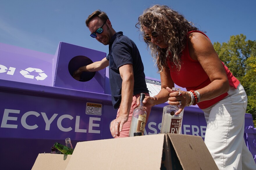 Akron residents Heather Pollock (right) and her husband Matt Neidert deposit glass bottles at a recycling bin that's part of the city's new glass drop off recycling program on Thursday, Sept. 21, 2023.