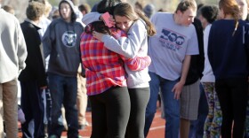 Students comfort each other at Arapahoe High School on Friday.