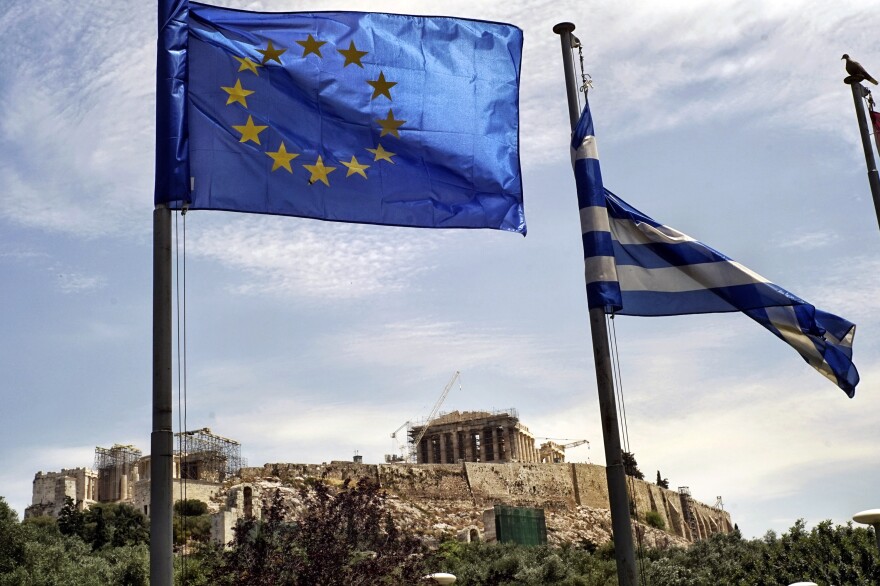 The EU and national flags fly in the foreground of the Parthenon, as Greek voters prepare to decide whether to continue negotiating for more international loans.