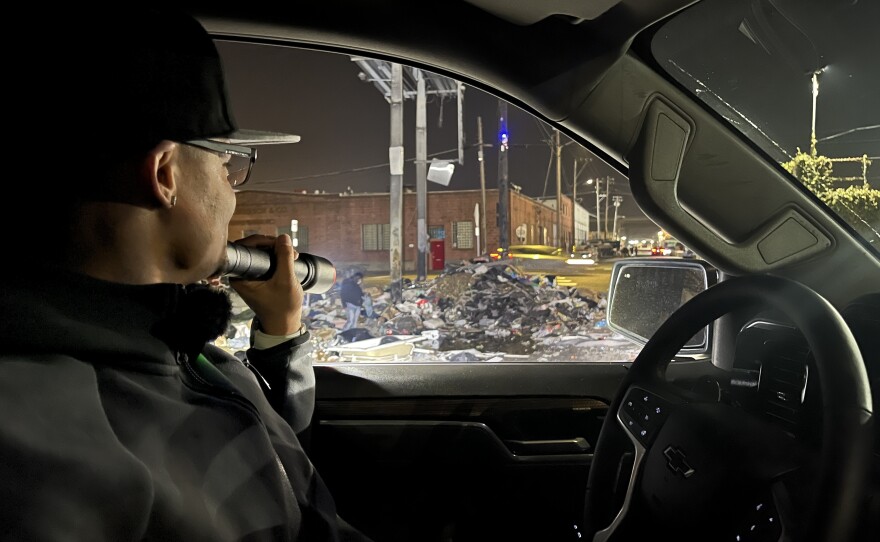 Vincent Williams shines flashlight on dump pile at 26th and Peralta in West Oakland