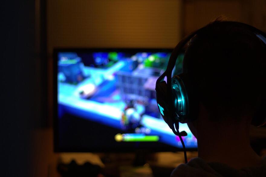 A person with a glowing headset plays a brightly colored video game in a dim room