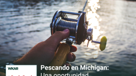En la imagen se puede observar el brazo de una persona de piel blanca agarrando una caña de pescar. La caña esta apuntada hacia un rio rodeado de arboles.  En el lado superior derecho de la imagen se encuentra escrito las siguientes palabras en blanco sobre un rectangulo de color negro: 'Pescando en Michigan: Una Oportunidad Para Desconectarse'. En la parte inferior derecha se puede observar un cuadrado pequeño  blanco en el cual está escrito 'WKAR' con el logo de  ¿Qué onda Michigan?. En el lado izquiero superior del cuadrado pequeño está escrito "repeticion" significando que este es un episodio repetido. 