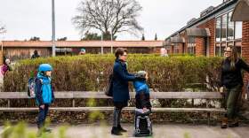 Parents and their children stand in line waiting to get inside Stengaard School north of Copenhagen, Denmark.