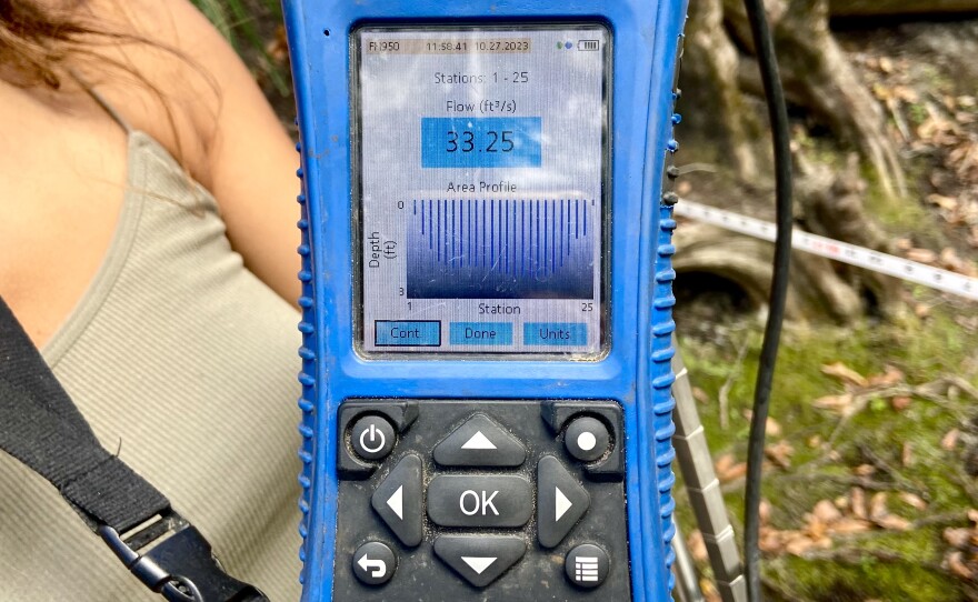 The electronic screen of a blue portable flow meter.