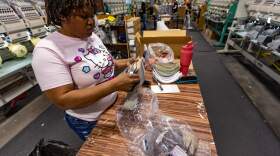 Musette Jean-Pierre, an immigrant from Haiti, inspects a hat on the factory floor of the New Bedford-based company Ahead. As she awaits her immigration hearing, she was granted authorization to work. (Jesse Costa/WBUR)