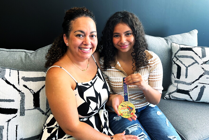 Mentor Rebeca Carrasquillo (left) and mentee Esmeraida Figueroa (right) are showing off their 2026 5k medal while inside the Big Brothers Big Sisters of Connecticut office in Hartford on September 19, 2026. The two earned the medal for participating in the Hispanic/Latinx Heritage Month 5k with Connecticut's chapter of Latinas in Motion, a community fitness group.