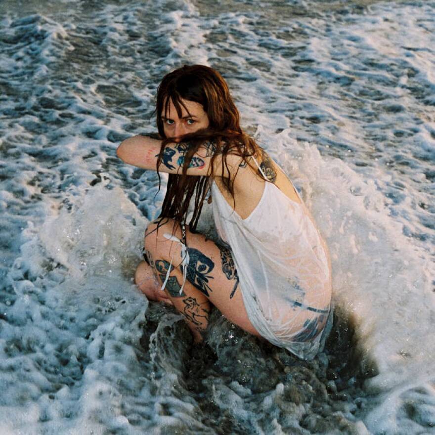 a woman in the ocean covering her face 