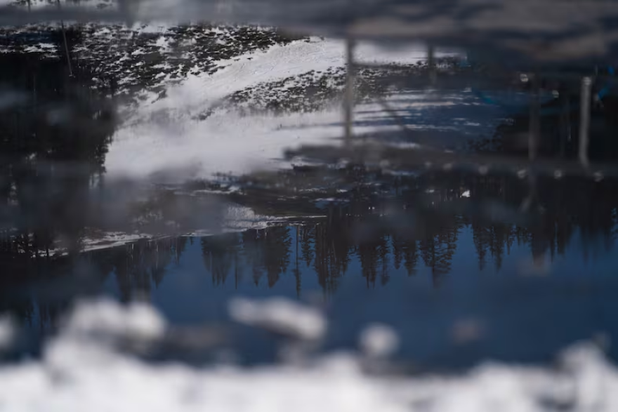Reflected in a pool of melting ice, dirt and grass show through the low snowpack at Mt. Hood Meadows on the resort’s second-to-last weekend in Mt. Hood, Ore., on April 4, 2026.