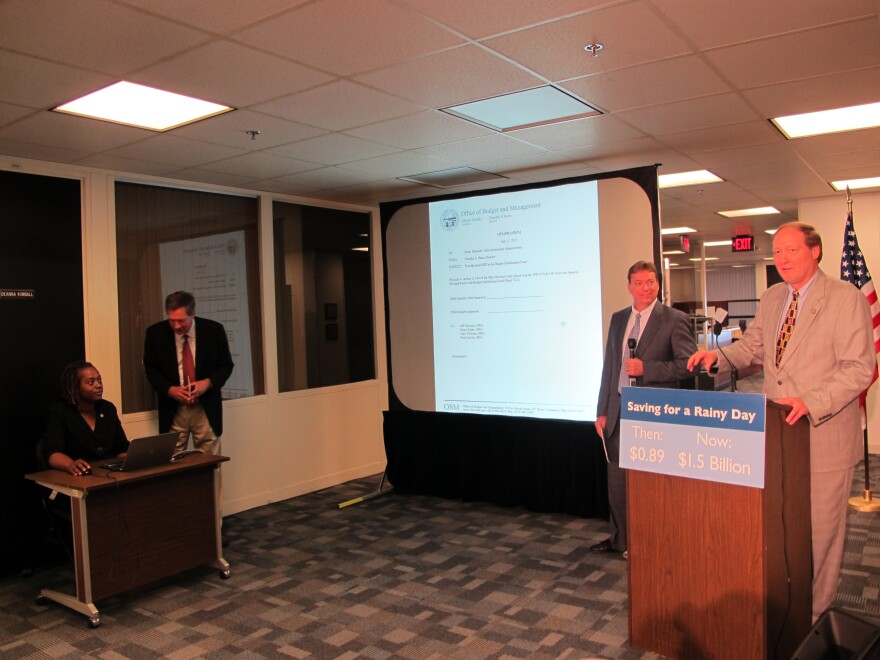 Then-Gov. John Kasich (standing, left) smiles as his budget director Tim Keen (right) finishes the first depost into the state's rainy day fund in July 2013. Kasich has notably said the fund had $.89 in it when he took office in 2011. [Karen Kasler]