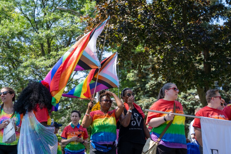 Excellus BlueCross BlueShield parade participants walk down the street with pride flags during the Pride parade and festival in Rochester on Saturday, July 19, 2025.