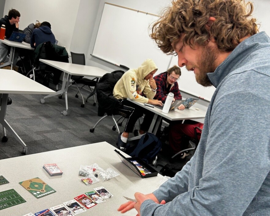 Justin Schrader demonstrates the baseball-themed game he created, called Seventh Inning Stretch. 
