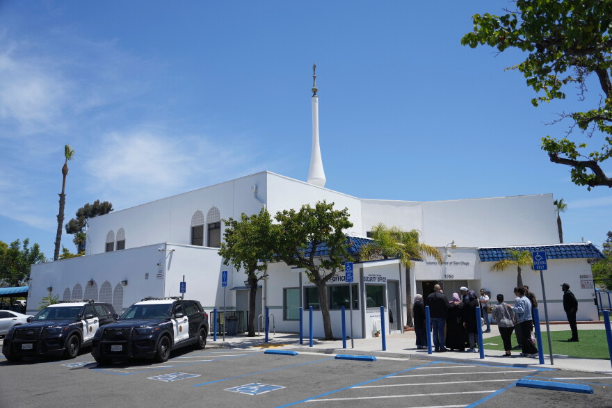 FILE - People gather as police vehicles are parked outside of the Islamic Center of San Diego, the day after a shooting, May 19, 2026, in San Diego.
