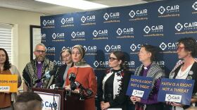 people stand behind a podium for a news conference