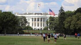 People walk on the Ellipse with the White House in the background on Monday in Washington.