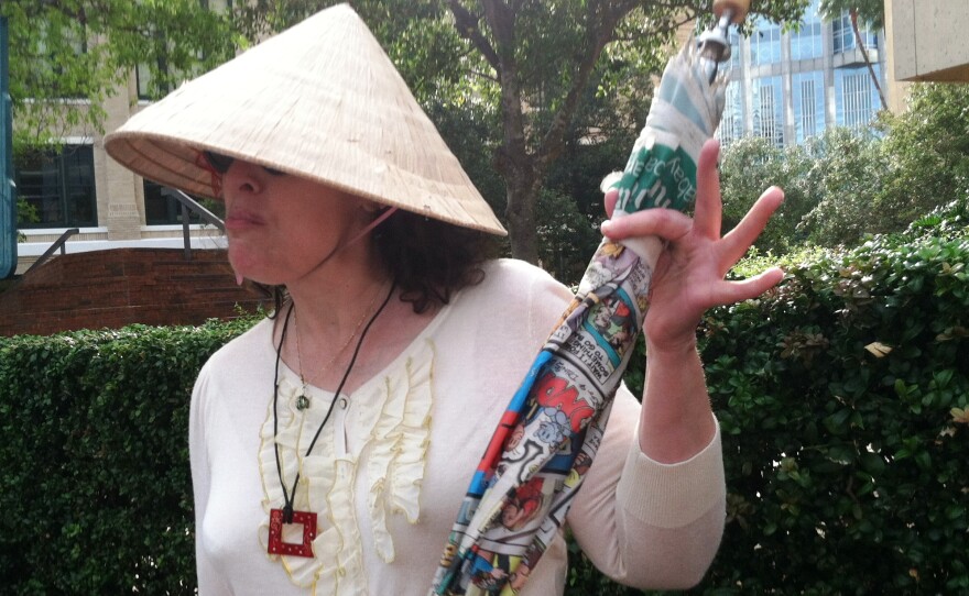 Maria Agosto holds up an umbrella and wears a broad-brimmed hat, two items that could be banned near downtown Tampa the week of the Republican National Convention.