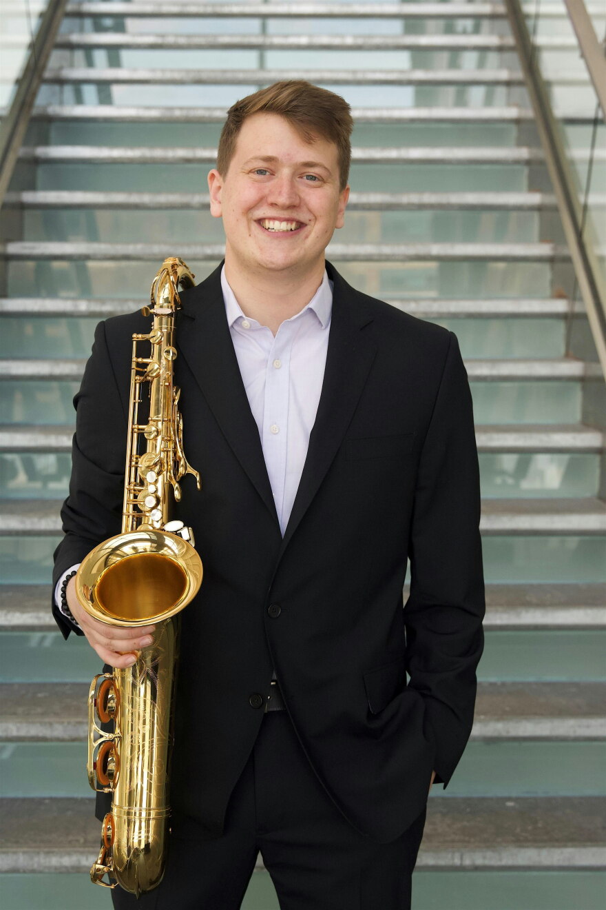 Photo of Grant Asklar posing with their saxophone.