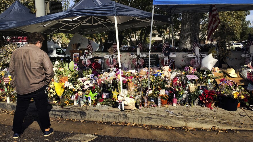 A passerby stops to look over a street side memorial to the shooting victims of the Borderline Bar in Thousand Oaks, Calif., on Tuesday. Investigators said the number of victims from the shooting at the country music bar could have been much higher based on the amount of ammunition the gunman carried.