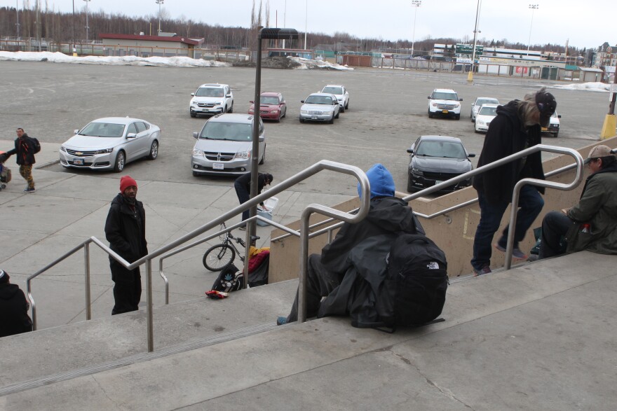 Homeless residents sit on the steps of the Sullivan Arena, as many are forced to leave the makeshift shelter. (Wesley Early/Alaska Public Media)