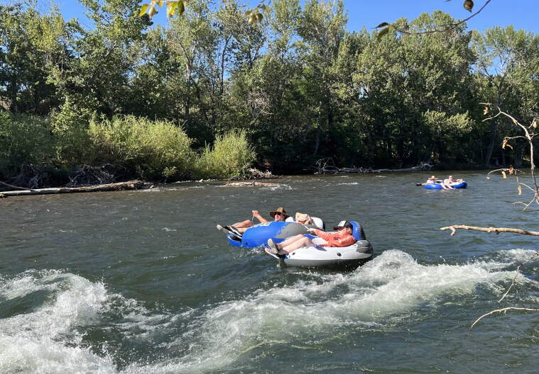 two pairs of people floating the Boise River on inner tubes. The pair in the foreground is about to enter a small section of whitewater.