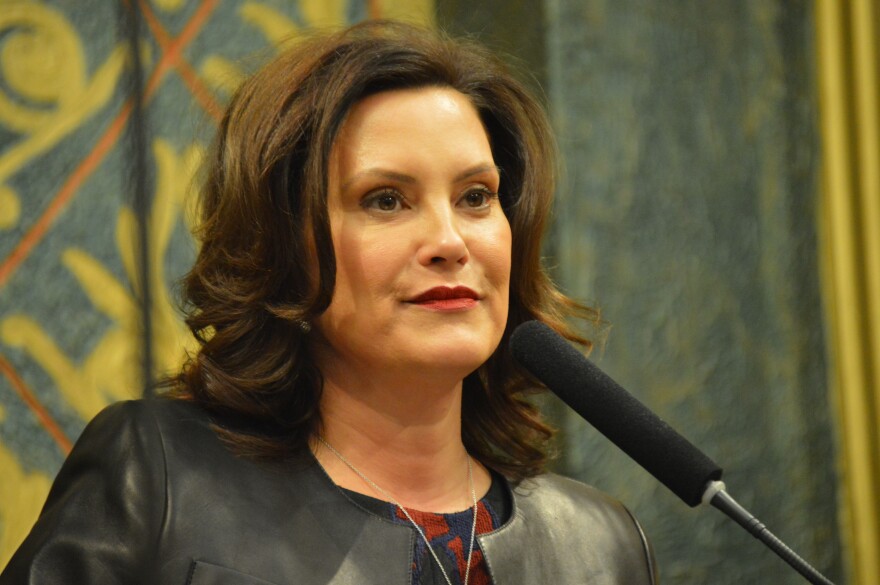 Governor Whitmer stands in front of a microphone 