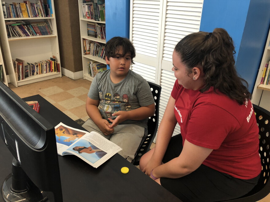 Stephanie Torres, 18, helps a student read "The Lion King" during a literacy class at the Boys & Girls Club summer camp in Kendall. She's also part of the Bank of America program.