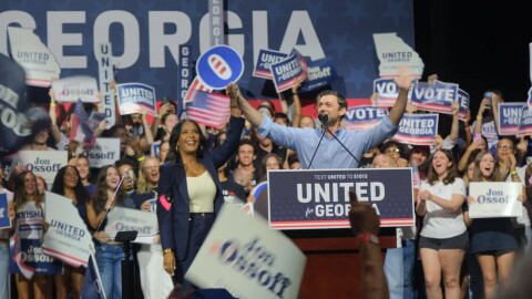 Sen. Jon Ossoff and former Atlanta Mayor Keisha Lance Bottoms take the stage together at the Georgia Theater. Behind them a crowd of young voters cheer with signs that say United for Georgia.