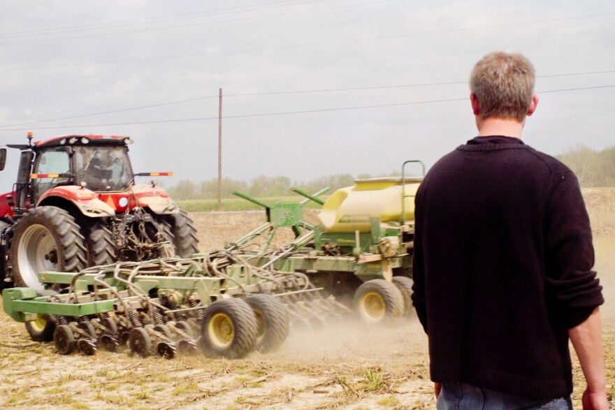Hans Schmitz watches as the soybean planter heads down the field Thursday morning in Posey County. His farm corporation is family-owned and operated, primarily working with corn and soy. This planter is operated by Scott Dougan.