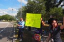 people standing on the side of the road on the USF campus with signs and balloons