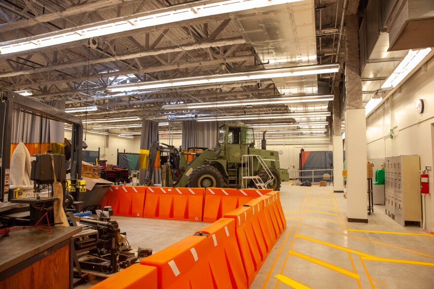 A large, green wheel loader, center, sits surrounded by other equipment students will use in class.