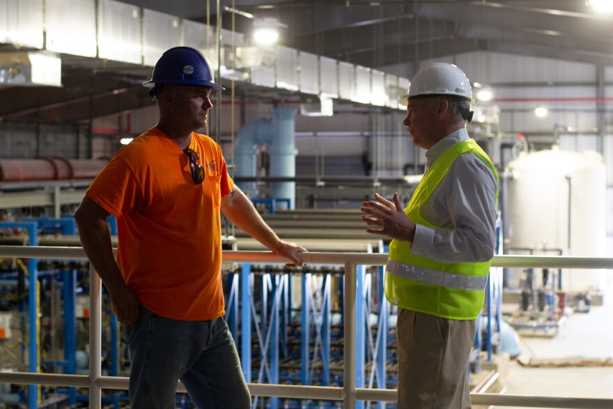 Brandon Abshire (left), chief operator of the plant, speaks with Kaine.