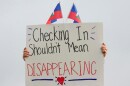 A protester holds a sign with Haitian flags during an "ICE out of Cincinnati" 