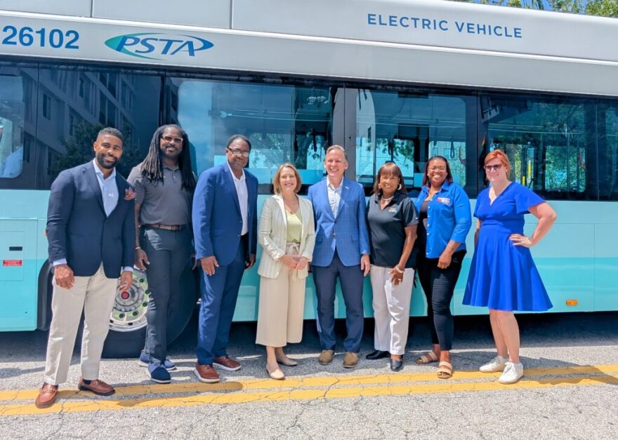 People wearing mainly blue standing in front of a blue bus.