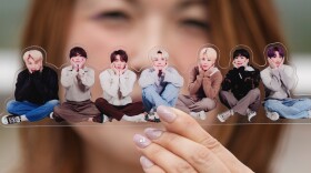 A fan poses with a group photo of BTS, also known as the Bangtan Boys, during a celebration marking the South Korean's K-pop band's 12th debut anniversary in Goyang, South Korea, June 13, 2025.